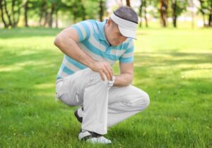 man holding his knee in pain while golfing